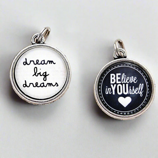 two sided round jewelry charm that says dream big dreams on one side and believe in yourself on the other side