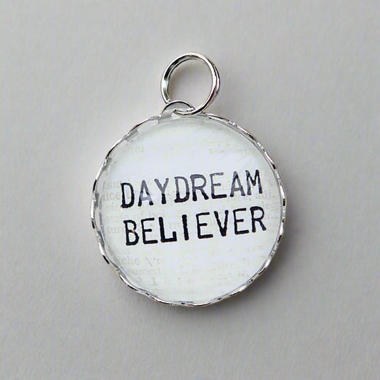 Round Jewelry charm that says Daydream Believer