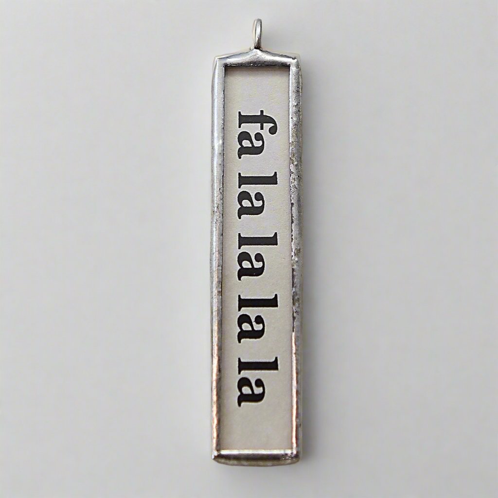 soldered two sided jewelry charm that says fa la la la la