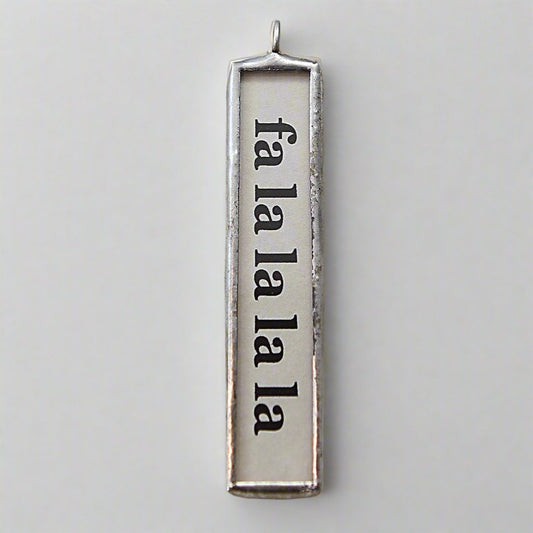 soldered two sided jewelry charm that says fa la la la la